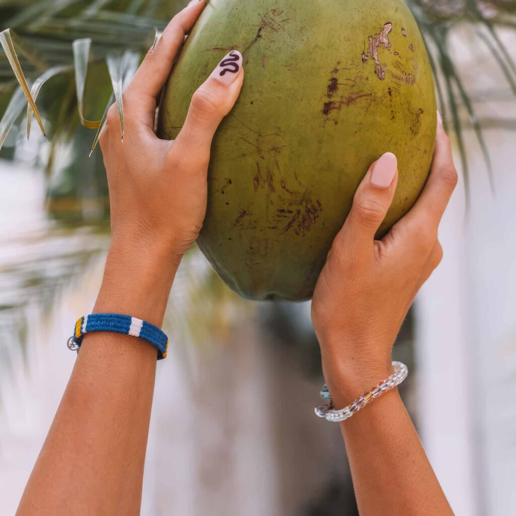 En kvinna med snygga armband håller en kokosnöt